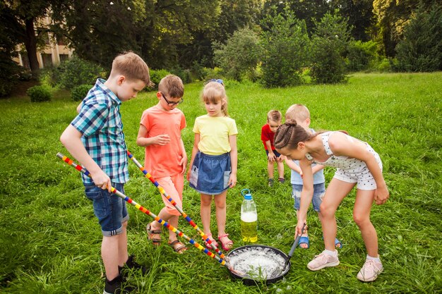 Kleine vrienden trainen om in de zomer grote zeepbellen te maken op een weiland