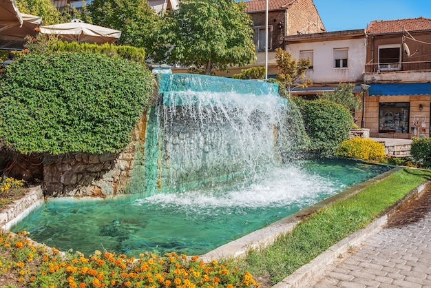 Kleine waterval in de stad Kerkyra (Corfu) op het eiland in de buurt van prachtige oude gebouwen, groene struiken. Griekenland.