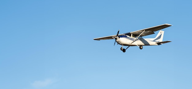 Kleine witte vliegtuig cessna-propeller die in het avondlicht vliegt in een heldere blauwe lucht