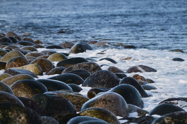 Kleine zeegolven breken tegen de stenen van de kust.