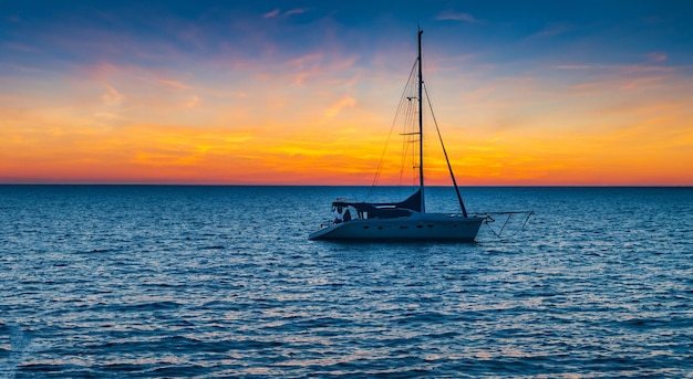 kleine zeilboten die bij zonsondergang op zee drijven