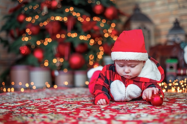 Kleine zes maanden oude baby verkleed als de kerstman. Het kind kijkt neer op de plaats voor inscriptie.