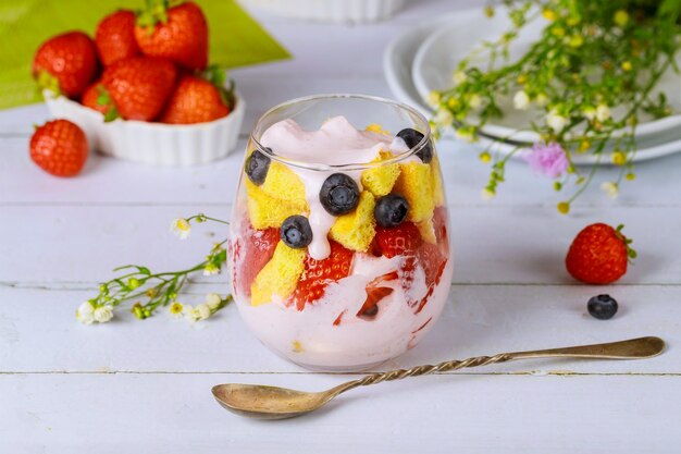 Kleinigheid met pondcake, aardbei en yoghurt in glas met lepel.