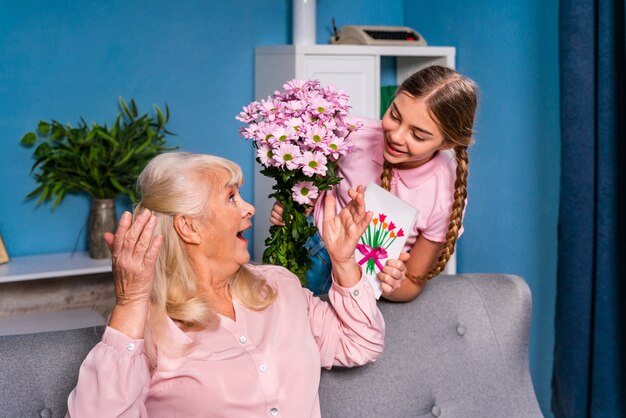 Kleinkind bloemen presenteren aan oma thuis, gelukkige momenten van het huiselijke leven