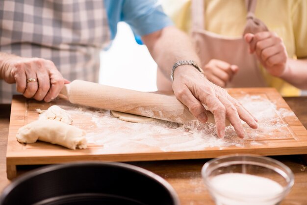 Kleinkind en grootvader koken en deeg maken voor koekjes met keukengerei in de keuken