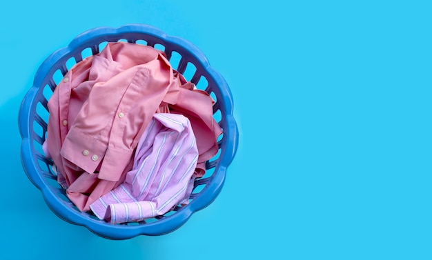 Kleren in een wasmand op blauwe ruimte. Kopieer ruimte