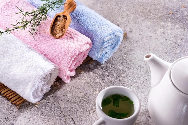 Kleur handdoeken met bloem, lepel zout, op bamboemat, badspabehandeling en groene thee op stenen tafel