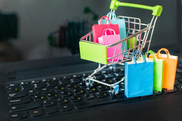 Kleur papieren boodschappentassen in winkelwagentje op een laptop computertoetsenbord