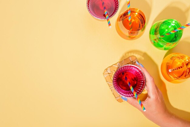 Foto kleurige cocktails op een gele tafel voor een regenboogfeest met regenboogdronkstrooien en feestaccessoires