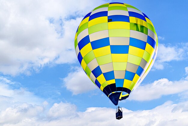 Kleurige luchtballon die over een blauwe hemel met witte wolken vliegt