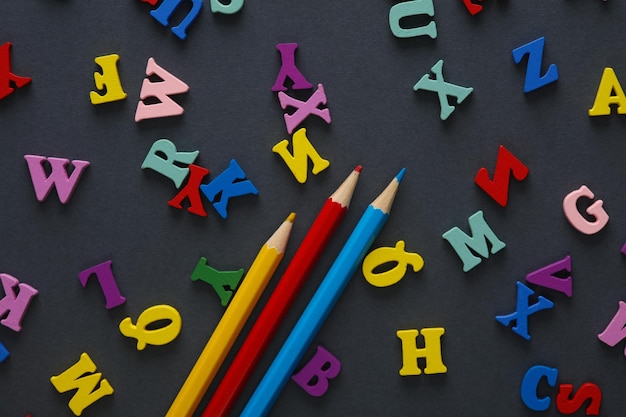 Kleurpotloden en veel letters op een grijze achtergrond Onderwijsconcept