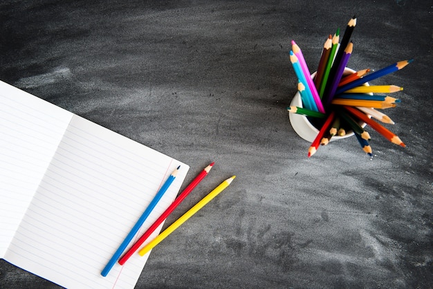 Kleurpotloden, voorbeeldenboek op zwarte bordachtergrond. terug naar school-concept.