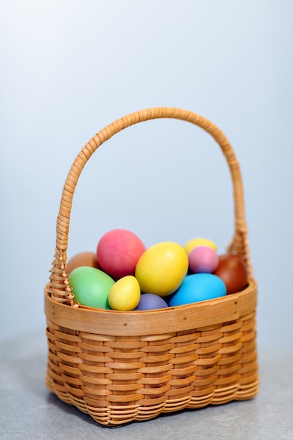 Foto kleurrijk beschilderde eieren voor de paasvakantie rieten mand op een lichte achtergrond