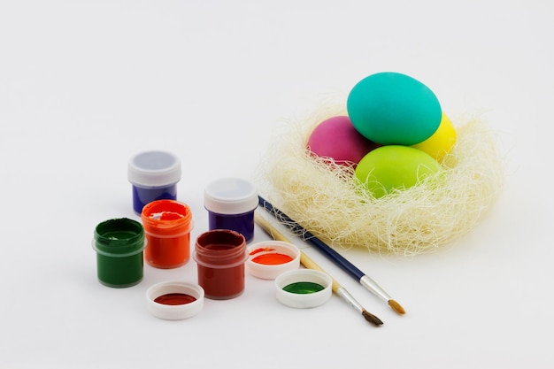 Kleurrijk beschilderde paaseieren in een nest met verf en een penseel