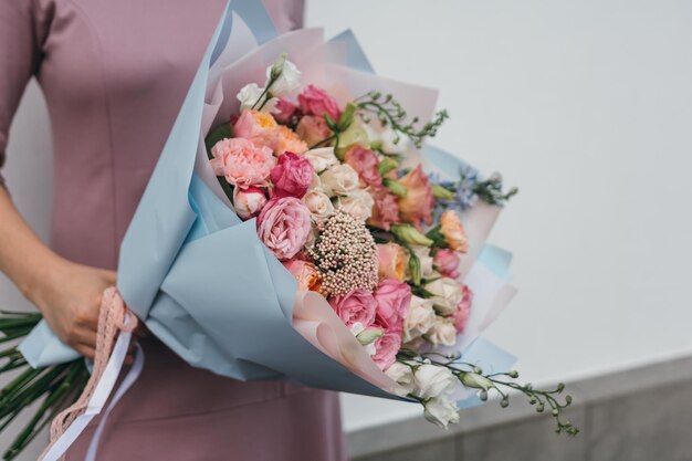 Kleurrijk boeket van verschillende verse bloemen in de handen van een bloemistvrouw