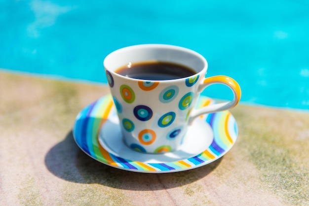 Kleurrijk kopje koffie aan het zwembad