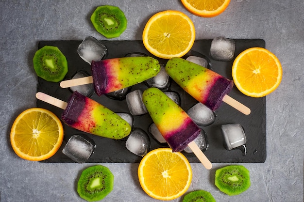 Foto kleurrijk laagjesroomijs op een stokje gemaakt van natuurlijk fruit. bovenaanzicht