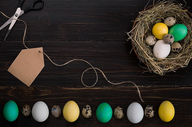 Kleurrijk paasei in nest op donker houten bord