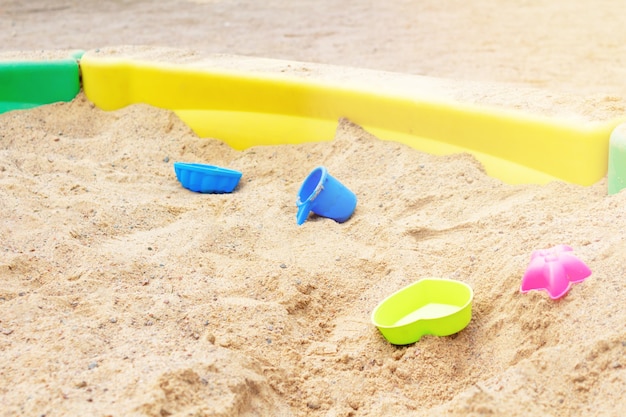 Kleurrijk plastic speelgoed ligt in zand in zandbak bij speelcomplex voor kinderen