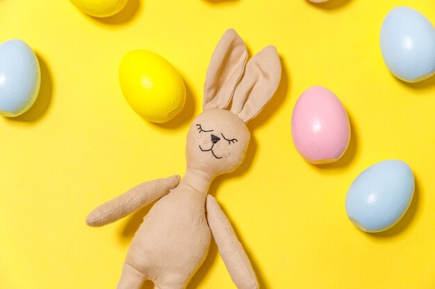 Kleurrijk verfraaid paaseieren en konijntjesstuk speelgoed dat op trendy geel wordt geïsoleerd