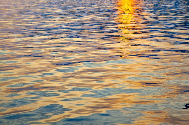 Foto kleurrijk wateroppervlak met rimpelingen bij zonsondergang. pittoreske natuurlijke achtergrond met ruimte voor je eigen tekst