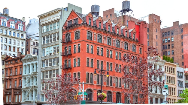 Kleurrijke bakstenen gebouwen, met ramen en brandtrap. Waterafzettingen op daken. NYC, VS.