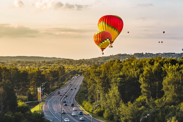 Kleurrijke ballonnen vliegen over het bos en de wegballonfestival ballonvlucht