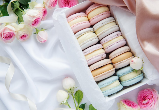 Kleurrijke bitterkoekjes in een geschenkdoos en rozen