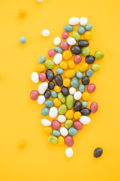 Kleurrijke chocolade snoep pillen geïsoleerd op gele achtergrond