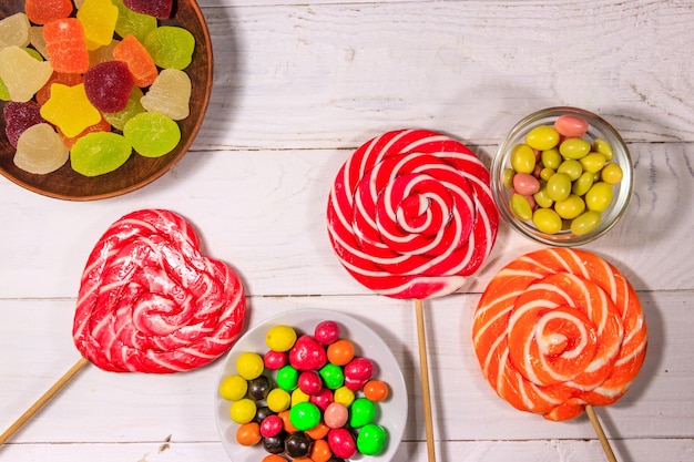 Foto kleurrijke chocoladesuikergoed, lolly's en gelei-snoepjes op witte houten tafel