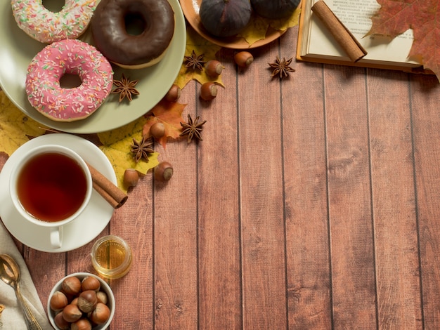 Kleurrijke donuts op de plaatherfst en een Kop thee op rustieke houten oppervlakte