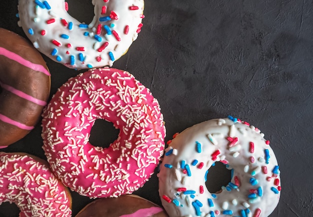 Kleurrijke donuts op zwarte stenen tafel. bovenaanzicht, kopieer ruimte.