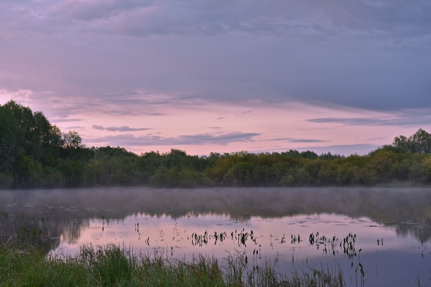 Kleurrijke en mistige dageraad boven een kleine rivier