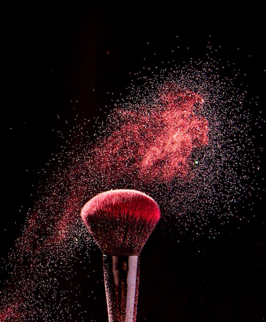 Foto kleurrijke explosie op make-upborstels op een zwarte achtergrond