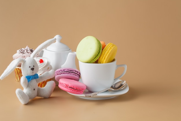 Kleurrijke Franse bitterkoekjes en kopje thee op beige achtergrond