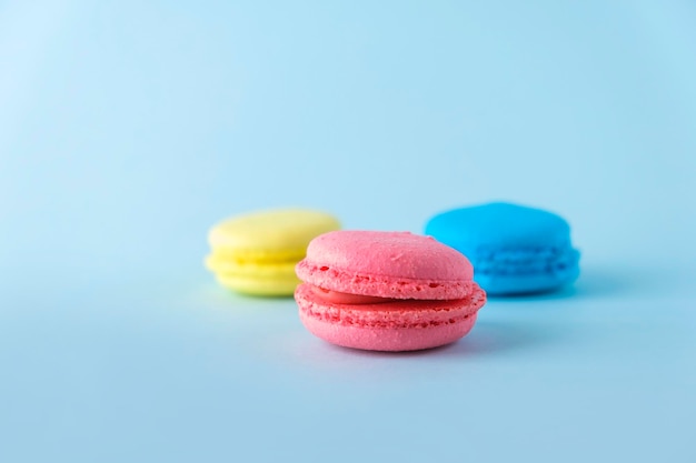 Kleurrijke franse macarons cookies bitterkoekjes op blauwe achtergrond Dessert vegetarische snoepjes close-up