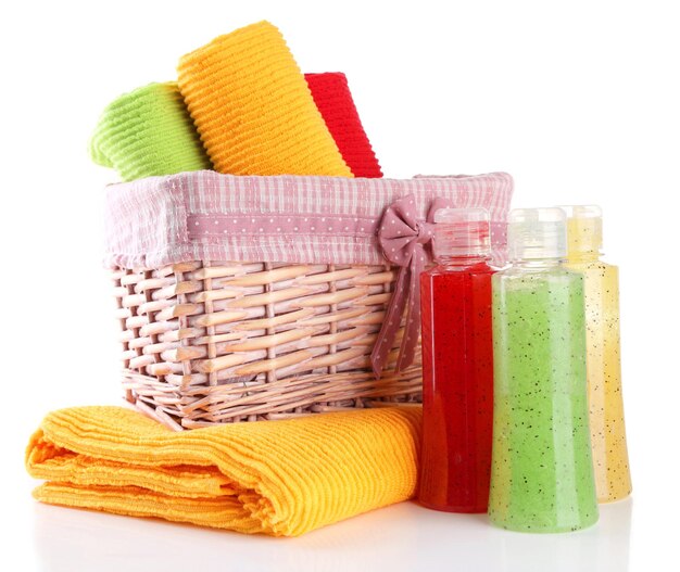 Kleurrijke handdoeken in mand en cosmetica flessen geïsoleerd op wit