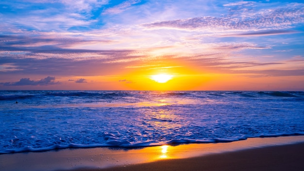 Kleurrijke hemel zonsondergang of zonsopgang Brandende kleurrijke lucht en glanzende golven op zandige kust Mooie lichtreflectie op zee-oppervlak Geweldig landschap of zeegezicht natuur achtergrond.