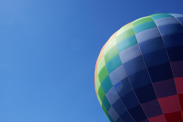 Kleurrijke heteluchtballon tijdens de vlucht tegen de blauwe hemel