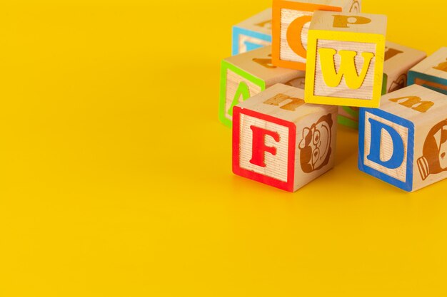Kleurrijke houten blokken met letters op een gele kleurenachtergrond