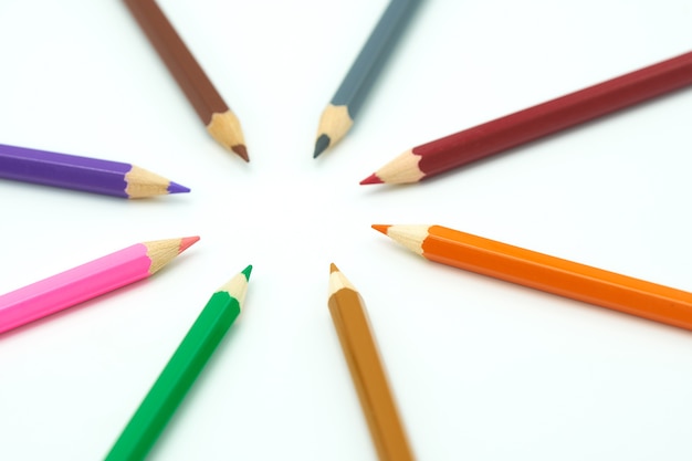 Kleurrijke houten potloden omringen een cirkel op een witte achtergrond.