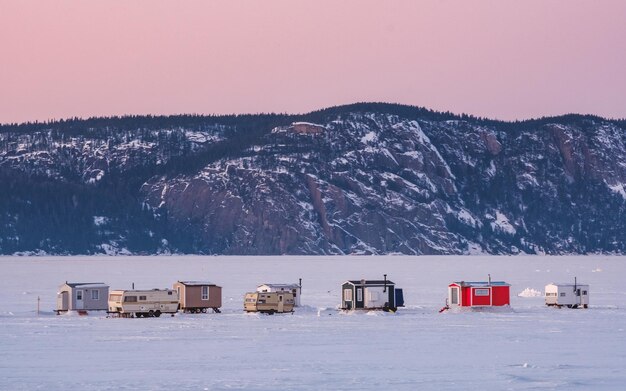 Kleurrijke ijsvishutten op de bevroren Saguenay-fjord bij zonsondergang in La Baie, Quebec (Canada)