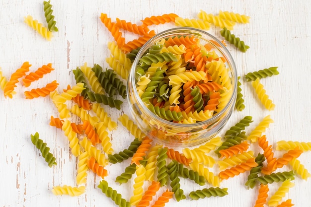 Kleurrijke Italiaanse fusilli pasta in een pot op een witte achtergrond.