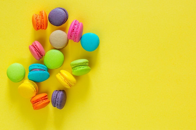 Kleurrijke macaroncakes op gele ruimte als achtergrond voor uw tekst