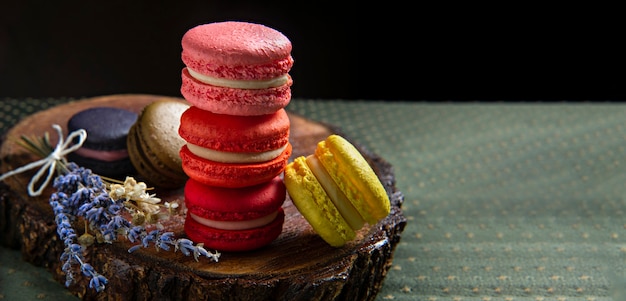 Kleurrijke macaronscakes met bloem op een houten basis. Kleine Franse taarten met kopieerruimte