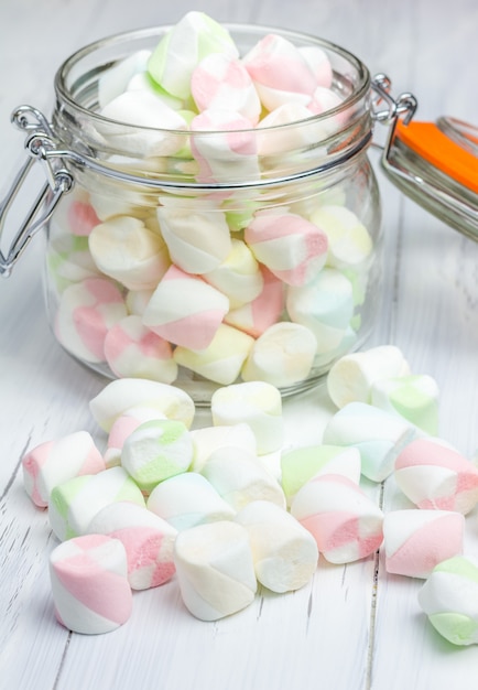 Kleurrijke marshmallows in glazen pot op lichte houten achtergrond