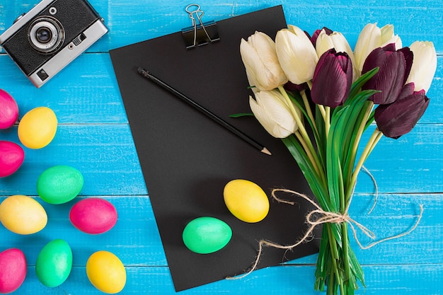 Kleurrijke paaseieren en boeket tulpen op houten achtergrond met ruimte voor een tekst