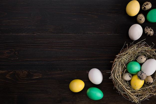 Kleurrijke paaseieren in nest op donkere vintage houten achtergrond