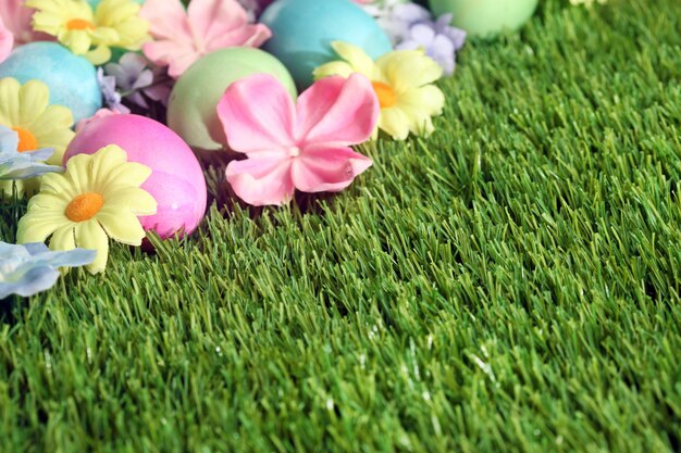 Foto kleurrijke paaseieren op gras met bloemenachtergrond