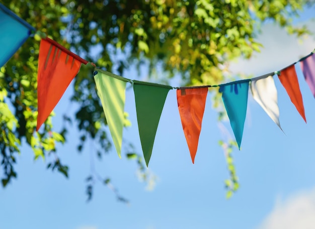 kleurrijke pennant string decoratie in groen boombladeren op blauwe hemel zomerfeest achtergrond AI gegenereerd